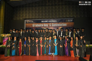 Graduates in caps and gowns on stage during RCM Global School BBA/BCA convocation 2025.