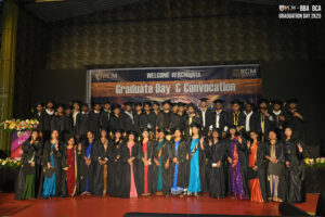 Graduates on stage in gowns and caps at RCM Global School's convocation celebration.