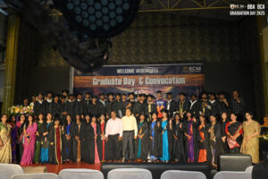 Graduation Ceremony and Convocation Celebration Graduates on stage in caps and gowns at an indoor ceremony, with a Graduate Day banner.