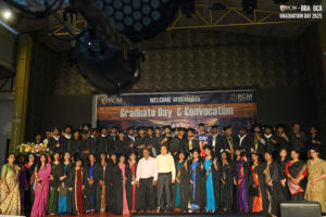 Graduates and faculty in traditional attire on stage under a "Graduate Day & Convocation" banner.