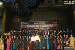 Group of graduates in caps and gowns on stage at RCM Graduate Day & Convocation event.