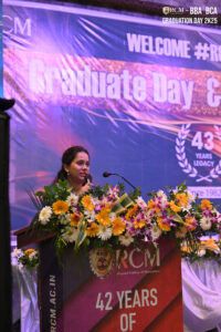 Person speaking at a podium with flowers at Regional College of Management graduation event.
