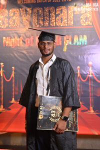 Graduate in cap and gown with diploma, backdrop of 2022-2025 welcome message, "Super Glam" event.