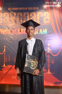 Person in graduation attire holding a certificate, standing before "Sayonara" backdrop.