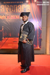 Graduate holding certificate on red carpet for RCM BBA/BCA 2025 farewell event.