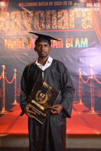person in gown and cap with certificate, red carpet backdrop.