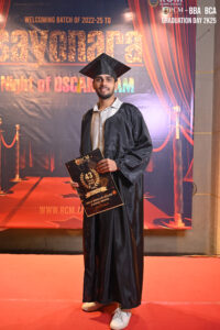 Graduate in cap and gown holding a certificate at an Oscar-themed BBA/BCA event backdrop.