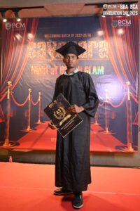 Person in graduation attire holding certificate on red carpet, RCM ceremony backdrop.