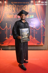 Graduate on red carpet holding a certificate with "Sayonara" banner in background.