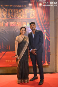 Man and woman on red carpet at RCM 2022-25 graduation event with "Sayonara" banner backdrop.