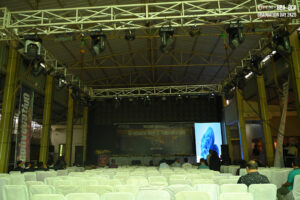 Large indoor venue ready for graduation; chairs, stage, lights, and screen in place.
