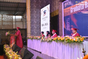 Graduation ceremony for BBA/BCA class of 2025 at RCM with speaker at podium.