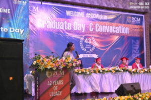 Person speaking at podium during RCM Global School's 43rd Graduate Day and Convocation event.