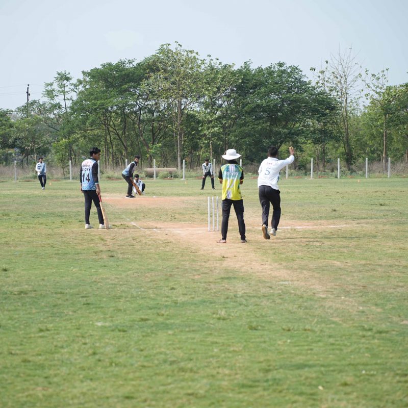Cricket match in progress during Ranbhoomi at Brahmastra 2025 with players in action and crowd cheering at Railway Sports Complex.